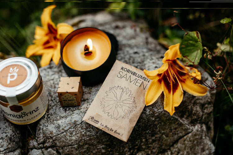 Produkte der Bee Happy Geschenkebox: Kornblumensamen, Knisterkerze, Honig & Honigpraline