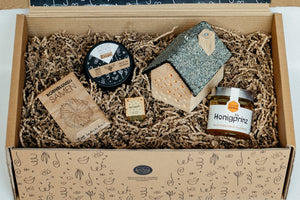 Übersicht der Honig-Geschenkbox im Karton: Samen, Kerze, Praline, Honig und Insektenhotel im Geschenkkarton arrangiert. 
