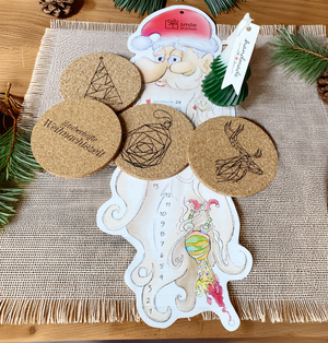 Kleine Weihnachtsgeschenkbox mit Kerze, Lebkuchen, festlichen Korkuntersetzern und Adventskalender auf festlich gedecktem Tisch - ideal als Kunden- oder Mitarbeitergeschenk