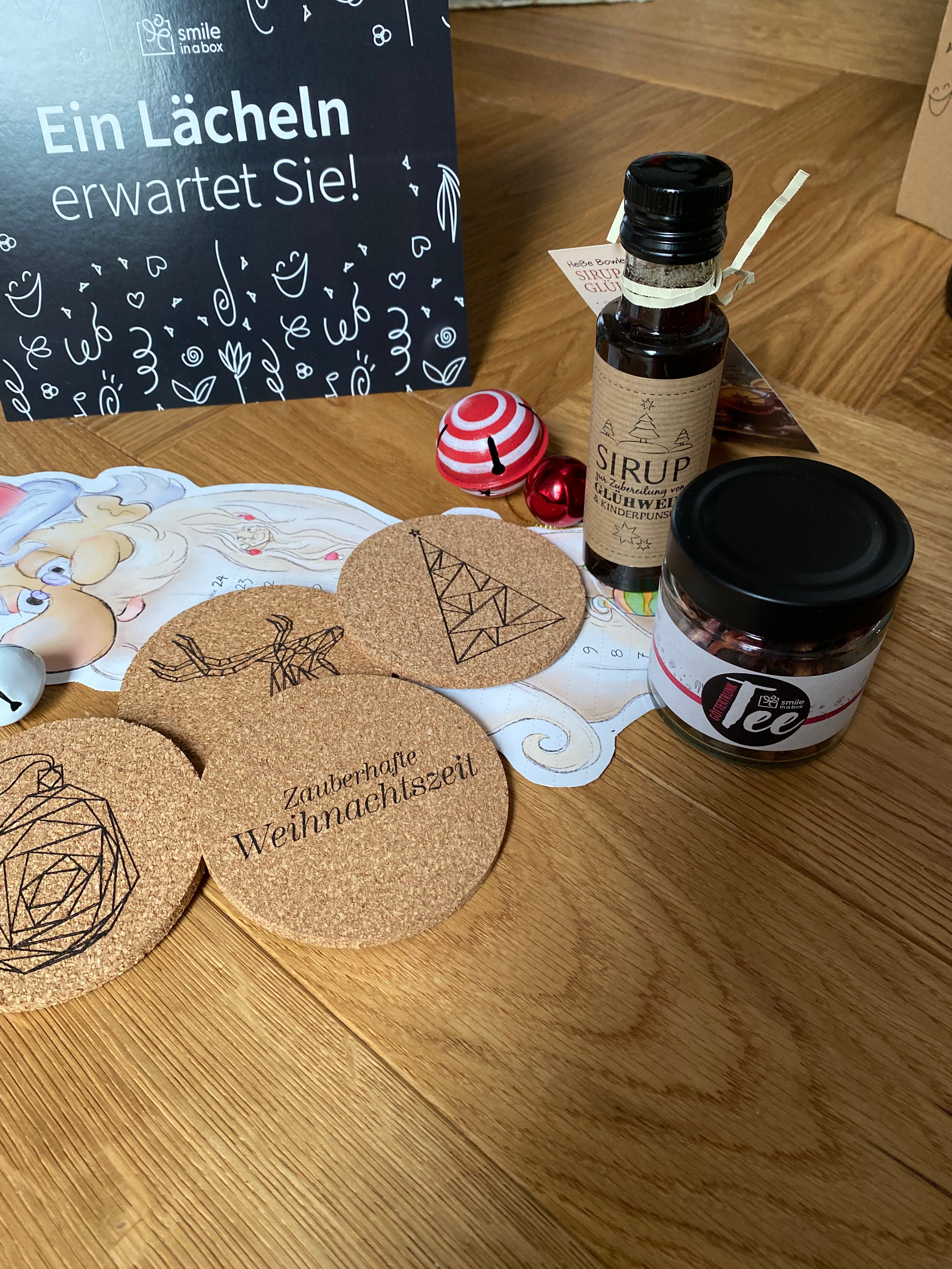 Größere Aufnahme der Weihnachtsgeschenkbox im Weihnachtsmarkt-Stil mit Tee, Mandeln, Sirup, Korkuntersetzern, Weihnachtskalender – ideal als Kundengeschenk