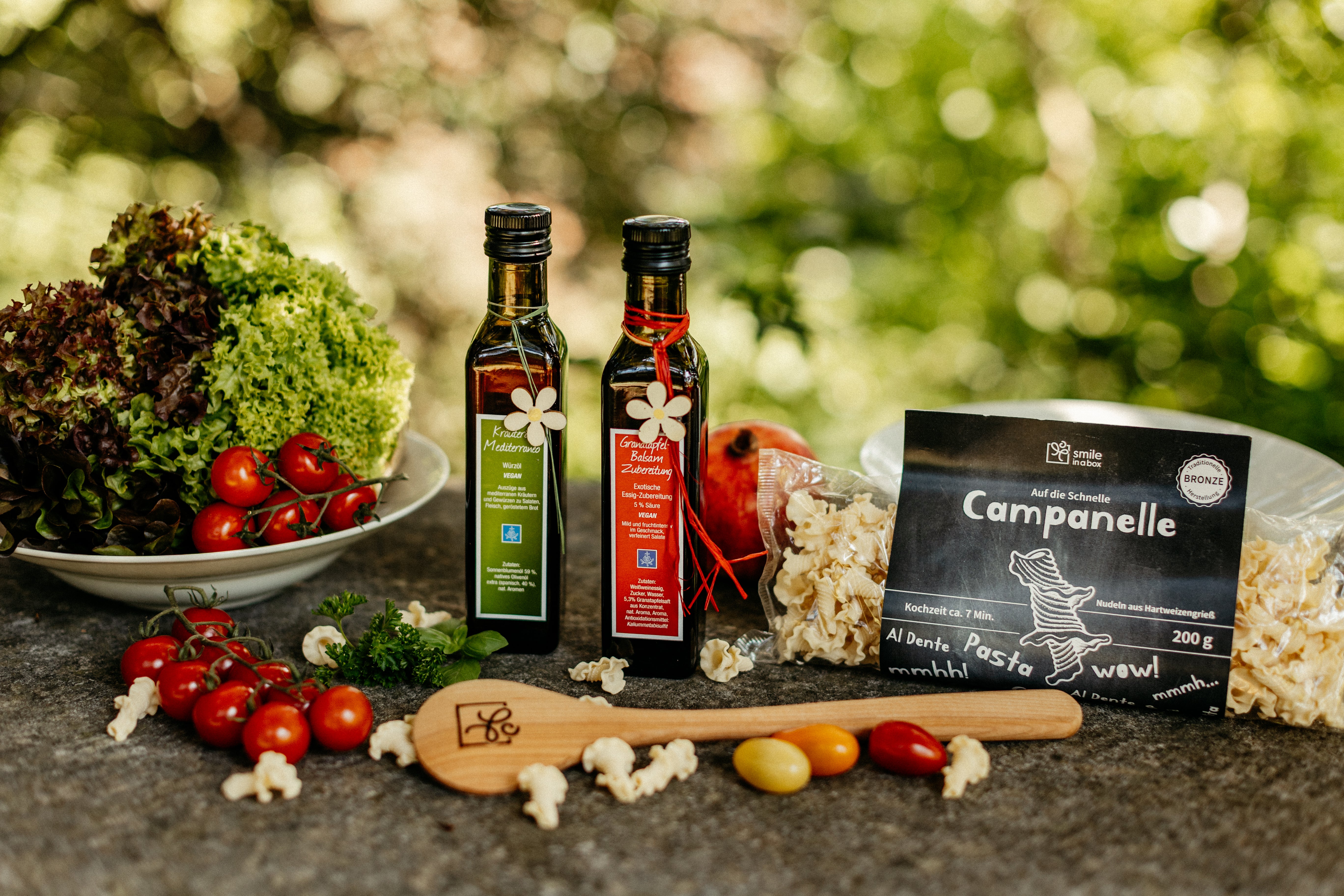 Sommerliche Geschenkbox mit Kräuteröl, Balsamicoessig, Kochlöffel, Pasta mediterran im Gartenflair angerichtet - Ein Geschenk perfekt für Kunden und Mitarbeiter