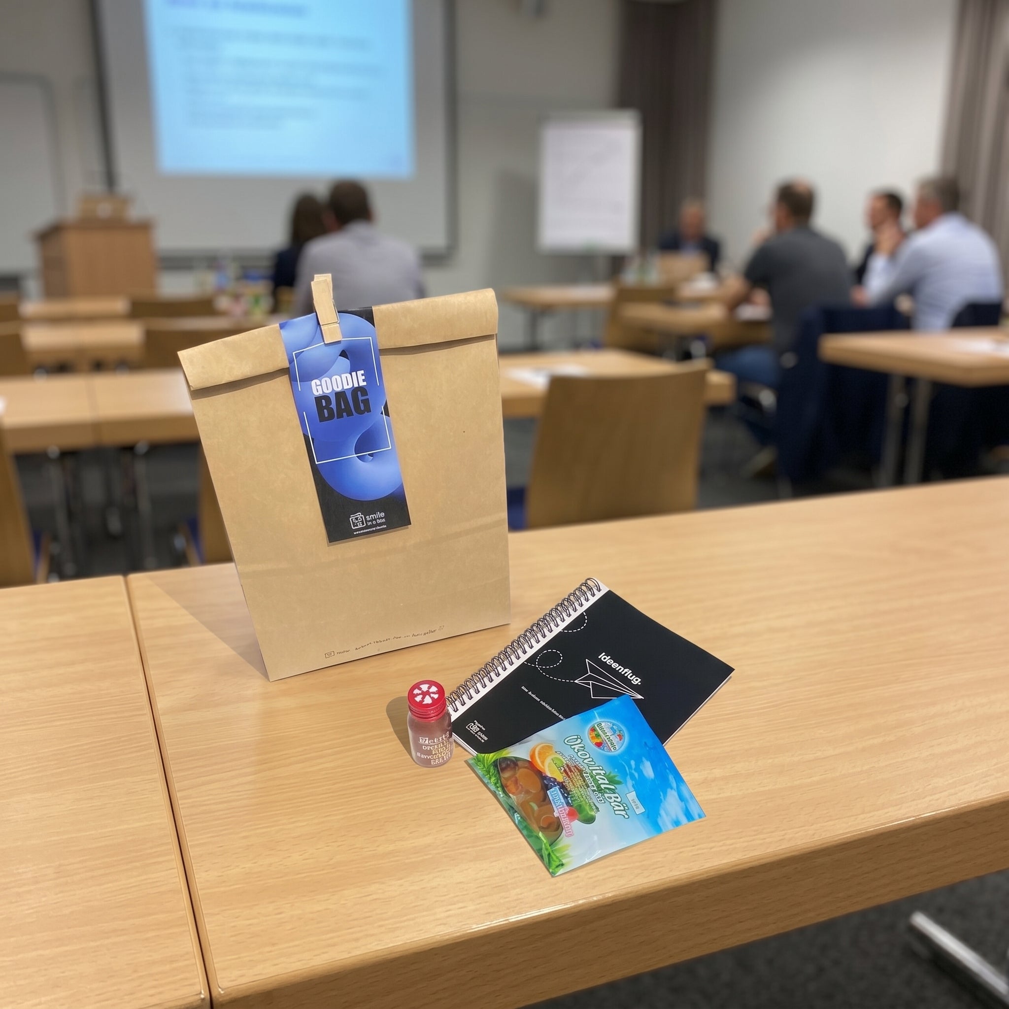 Seminartüte mit Goodies wie Notizbuch, Gummibärchen und Ingwershot für Teilnehmer bei Fortbildungen, Training und Coachings.