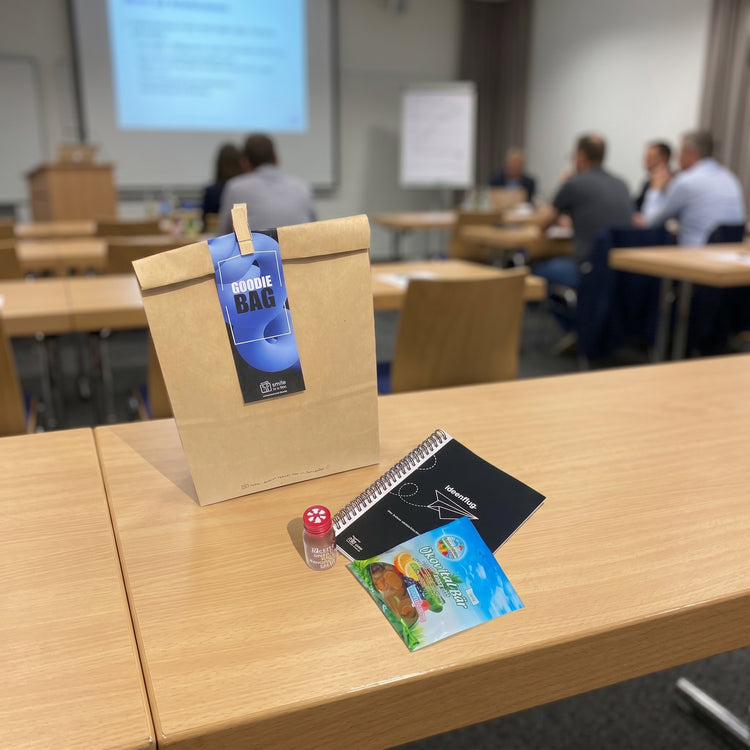Seminartüte mit Goodies wie Notizbuch, Gummibärchen und Ingwershot für Teilnehmer bei Fortbildungen, Training und Coachings.