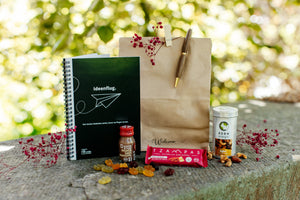 Ein herzliches Willkommensgeschenk für neue Kollegen - in Tüte mit Ingwershot, Notizbuch, Kugelschreiber, Nussmischung, Müsliriegel